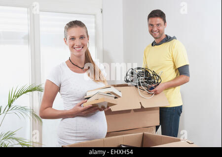 Schwangere Frau Verpackung mit ihrem Ehemann beim Umzug in neue Wohnung, Bayern, Deutschland Stockfoto