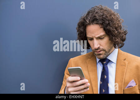 SMS junger Geschäftsmann langen lockigen Haare Handy Stockfoto