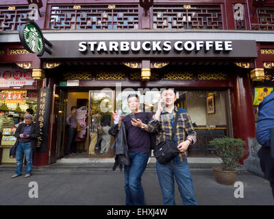 Zwei chinesische junge Männer außerhalb ein Starbucks-Café befindet sich in der Yuyuan Tourist Mart, Shanghai, China Stockfoto