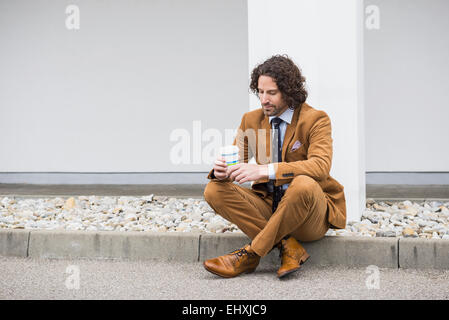 Besorgt Geschäftsmann Kaffee gehts am Straßenrand sitzen Stockfoto