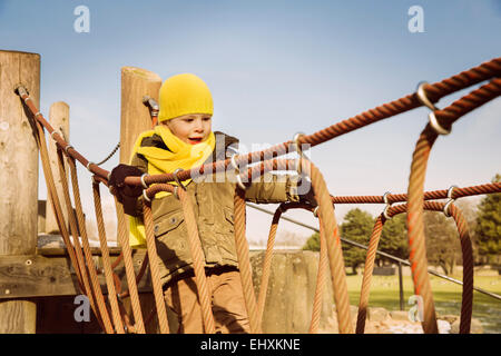 Kleinen Jungen zu Fuß entlang einer Hängebrücke auf einem Spielplatz Stockfoto