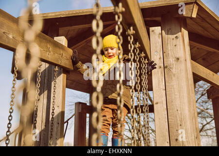 Kleinen Jungen zu Fuß entlang einer Hängebrücke auf einem Spielplatz Stockfoto