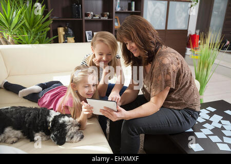 Frau mit ihren beiden Töchtern spielen auf eine digitale Tablet in ein Wohnzimmer, Bayern, Deutschland Stockfoto