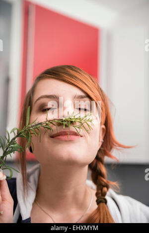 Frau riechen einen Zweig Rosmarin, München, Bayern, Deutschland Stockfoto