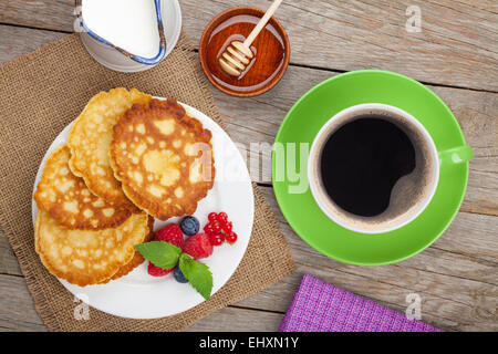 Pfannkuchen mit Himbeeren, Heidelbeeren, Milch und Honig Sirup. Auf Holztisch Stockfoto