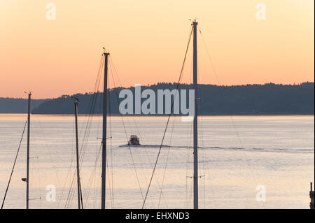 Power Boot Sets heraus auf eine Abendfahrt mit Segelboot Masten im Vordergrund Stockfoto