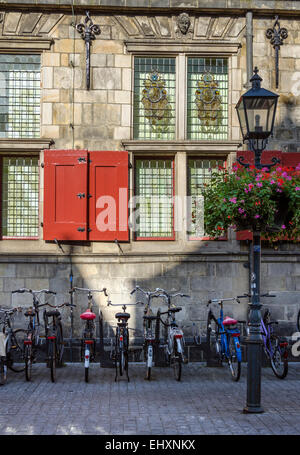 Ein Seitenfenster auf das Rathaus in Delft mit Fahrrädern unter geparkt. Stockfoto