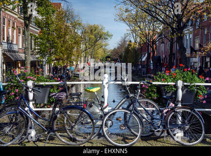 Fahrräder parken gegen das Geländer auf einer Brücke über einen Kanal in Delft, Niederlande. Stockfoto