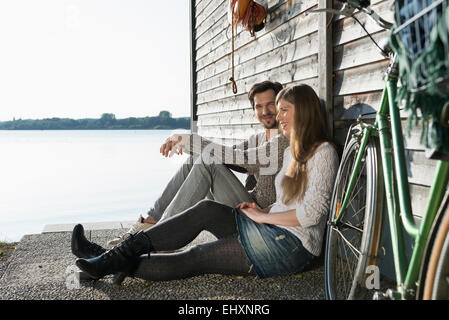 Junges Paar sitzt entspannende See Bootshaus Stockfoto