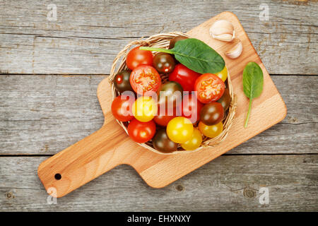Bunte Kirschtomaten auf Schneidebrett über Holztisch Hintergrund Stockfoto