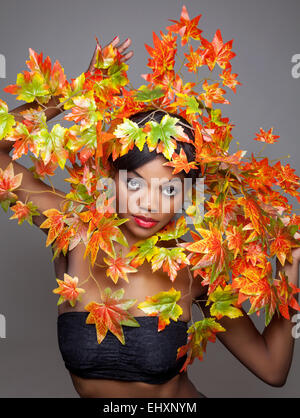 Schöne junge Frau eingewickelt im Herbst Blätter Stockfoto