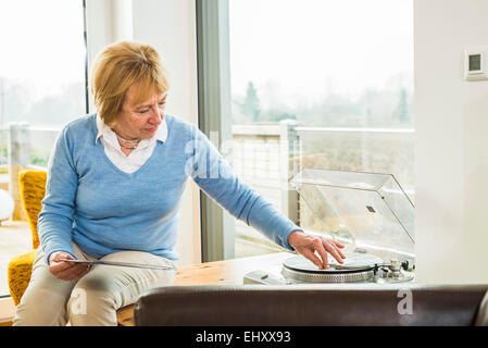 Ältere Frau zu Hause anziehen Plattenspieler record Stockfoto