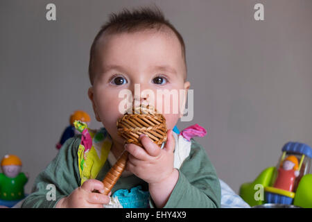 8 Monate altes Baby Mädchen, umgeben von Spielzeug in der Babywippe, Weinen Stockfoto