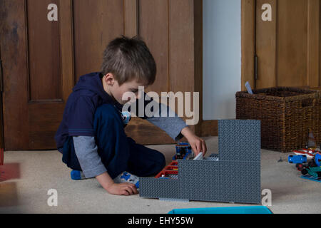 Jungen im Alter von vier Jahren spielen mit Lego-Bausteinen im Schlafzimmer Stockfoto