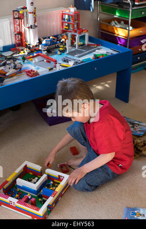 Jungen im Alter von vier Jahren spielen mit Lego-Bausteinen im Schlafzimmer Stockfoto