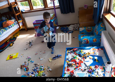 Jungen im Alter von vier Jahren spielen mit Lego-Bausteinen im Schlafzimmer Stockfoto