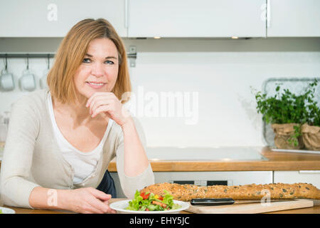 Ältere Frau sitzt in Küche Stockfoto