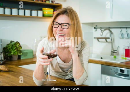 Ältere Frau in Küche trinken Rotwein Stockfoto