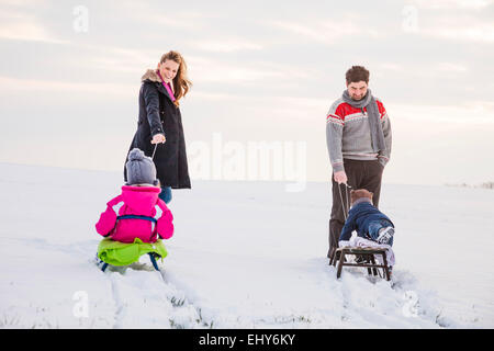 Glückliche Familie im Schnee Rodeln Stockfoto