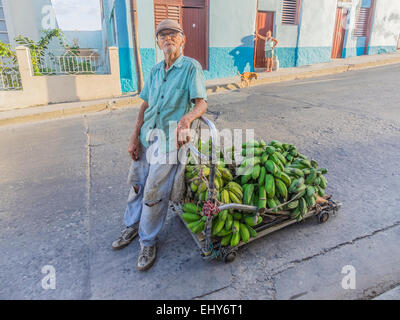 Ein Alter Hispanic Mann zieht seinen 4-Rad-Wagen beladen mit grünen Bananen durch die Straßen von Santiago De Cuba. Stockfoto