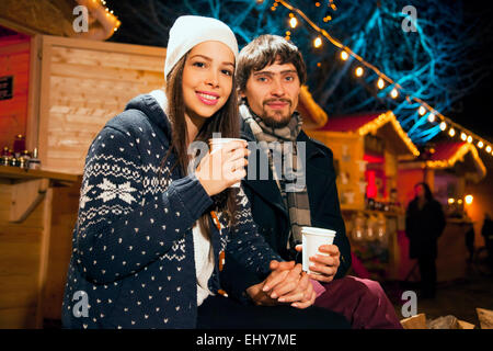 Junges Paar trinken Punsch am Weihnachtsmarkt Stockfoto