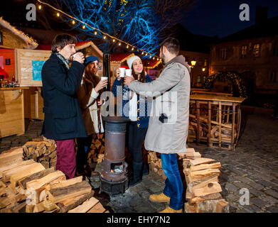 Vier Freunde Aufwärmen Ofen am Weihnachtsmarkt Stockfoto