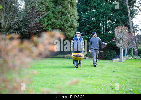 Senior woman drängen Schubkarre im Garten, Bournemouth, Grafschaft Dorset, UK, Europa Stockfoto