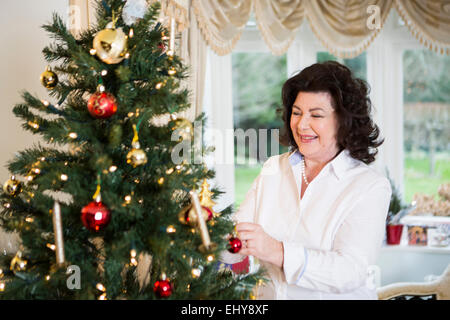 Ältere Frau dekorieren Weihnachtsbaum Stockfoto