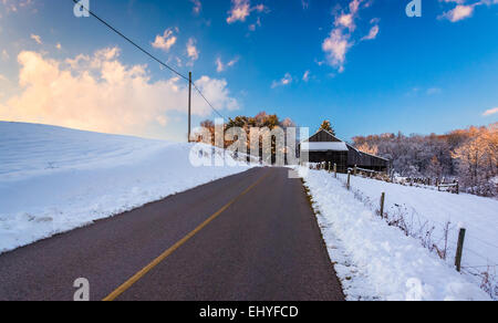 Scheune und Schnee bedeckt Felder entlang einer Landstraße im ländlichen York County, Pennsylvania. Stockfoto