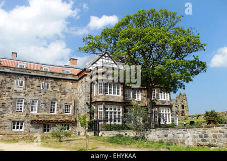 Malerische Aussicht auf ein englisches Herrenhaus mit Whitby Abtei im Hintergrund, North Yorkshire, England. Stockfoto