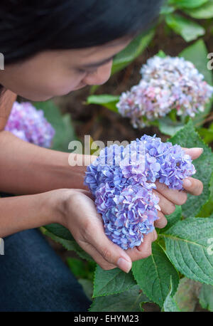 Junge Frau mit Herz geformten Blüten in der hand Stockfoto