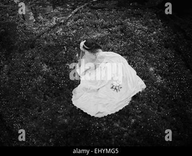 Draufsicht auf eine junge Frau sitzt auf dem Waldboden Stockfoto
