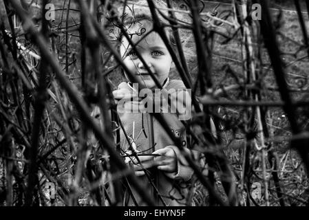 Lächelndes Mädchen versteckt in den Büschen Stockfoto