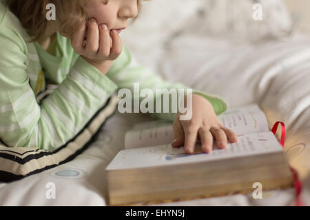 Junge liegend im Bett lesen Stockfoto