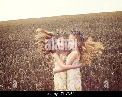 Mädchen, das in einem Weizenfeld steht und ihr Alter Ego umarmt Stockfoto