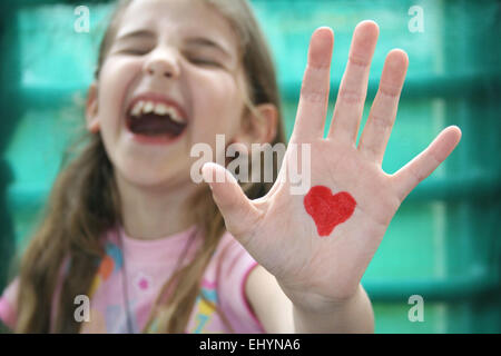 Mädchen mit einem Herzen auf der Handfläche von ihrer Hand gezeichnet Stockfoto