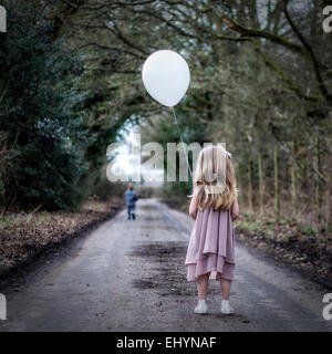 Rückansicht des Mädchens mit einem Ballon Blick auf junge auf der Flucht vor ihr Stockfoto