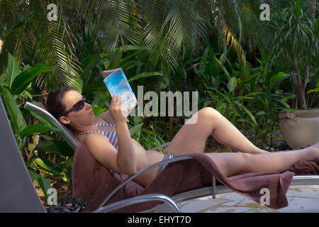 Junge Frau, Sonnenbaden und Buch Stockfoto