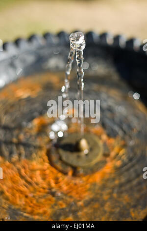 Wasser fließt aus einem Hahn in einem öffentlichen Brunnen und in einem rostigen Teller fallen. Selektiven Fokus Stockfoto