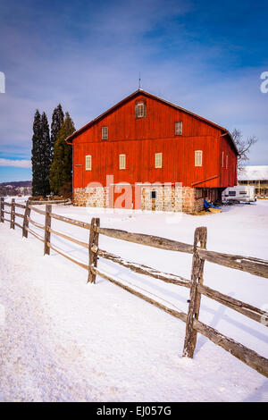 Rote Scheune und Zaun in einem verschneiten Hof-Feld in ländlichen Adams County, Pennsylvania. Stockfoto