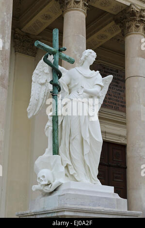 Eine Engelsstatue hält ein hölzernes Kreuz außerhalb der Karlskiche (St-Charles) Kirche, Wien, Österreich. Stockfoto