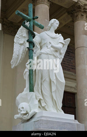 Eine Engelsstatue hält ein hölzernes Kreuz außerhalb der Karlskiche Kirche, Wien, Österreich. Stockfoto