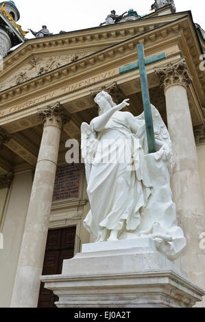 Eine Engelsstatue hält ein hölzernes Kreuz außerhalb der Karlskiche (St-Charles) Kirche, Wien, Österreich. Stockfoto