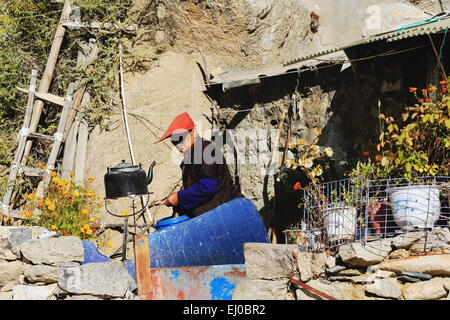 DREPUNG, TIBET, CHINA - 19. Oktober: Tibetisch-buddhistische Nonne bereitet Tee in eine metallische Teekanne auf der Außenseite der Hütte-Drepung monas Stockfoto