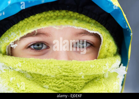 Nahaufnahme von gebündelt, blauen Augen kleiner Junge mit Schnee Flocken details Stockfoto