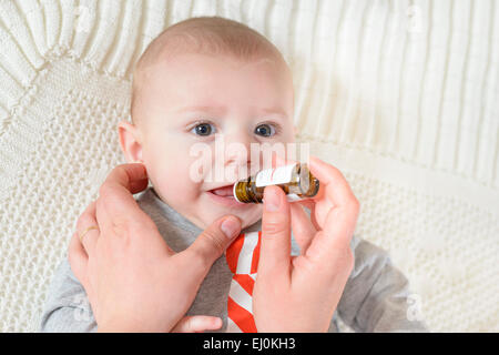 Niedliches Baby bekommt Medizin aus einer kleinen Flasche Stockfoto