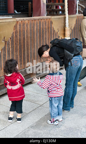 Im Yasaka-Schrein, einem Shinto-Tempel im Gion-Viertel von Kyoto, Japan. Eine junge Mutter bringt ihren beiden kleinen Kindern das Beten bei Stockfoto