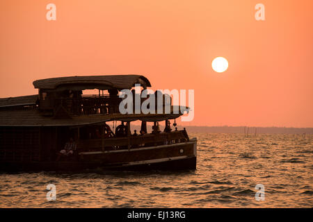 Ein Hausboot in der Silhouette bei Sonnenuntergang am Vembanad See in Kumarakom, Kerala Indien Stockfoto