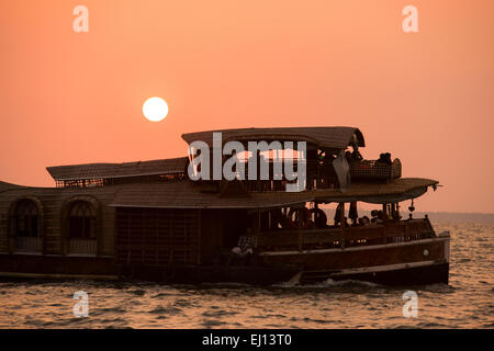 Ein Hausboot in der Silhouette bei Sonnenuntergang am Vembanad See in Kumarakom, Kerala Indien Stockfoto