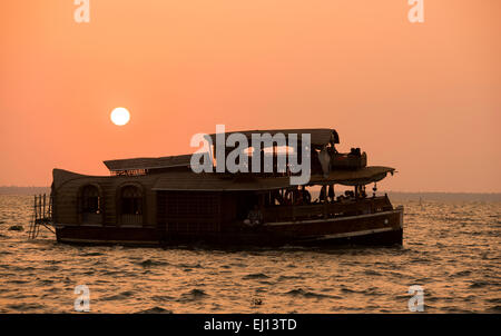 Ein Hausboot in der Silhouette bei Sonnenuntergang am Vembanad See in Kumarakom, Kerala Indien Stockfoto